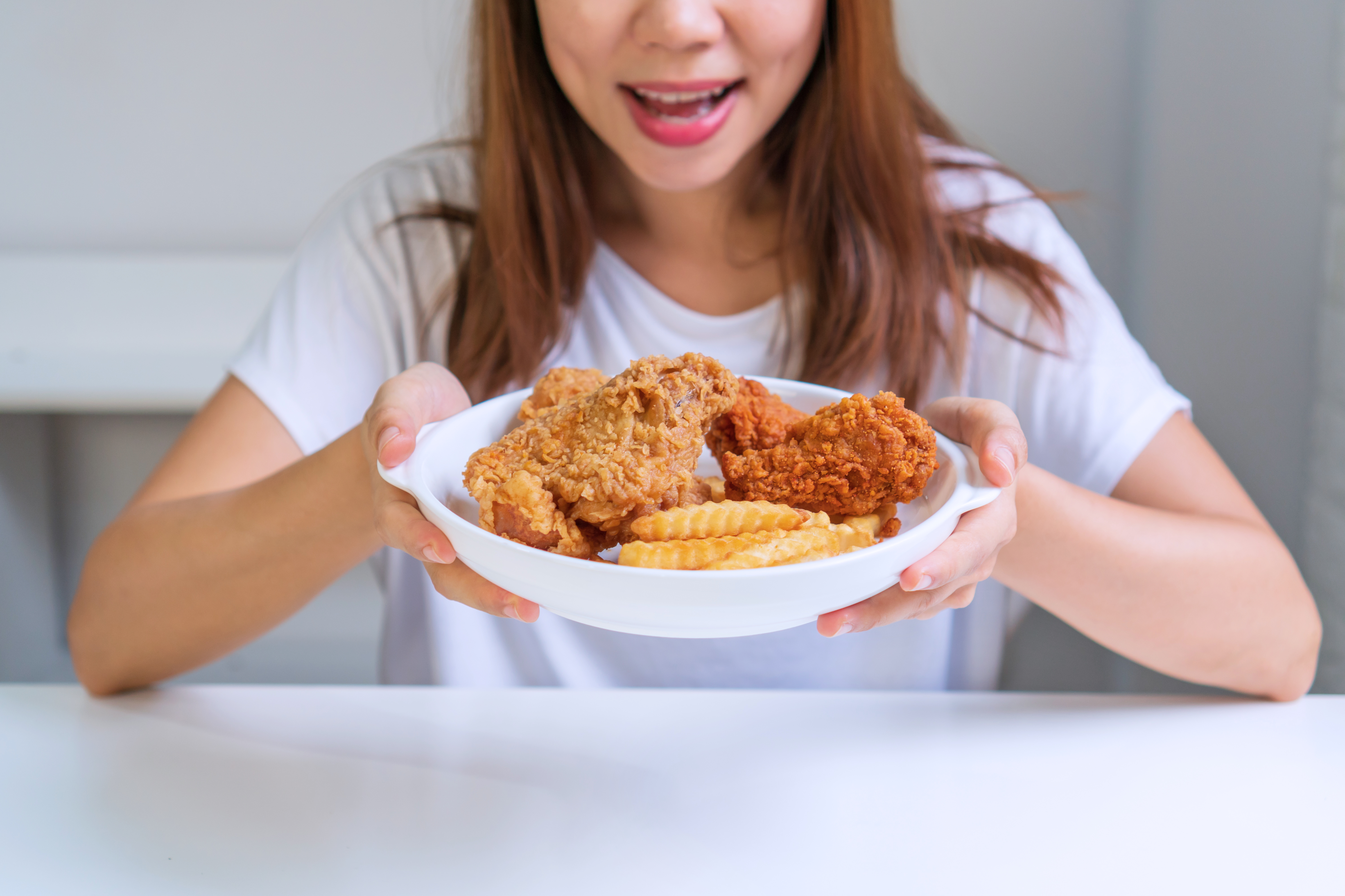 Young Aisan woman in white T-shirt holding a plate of her favour